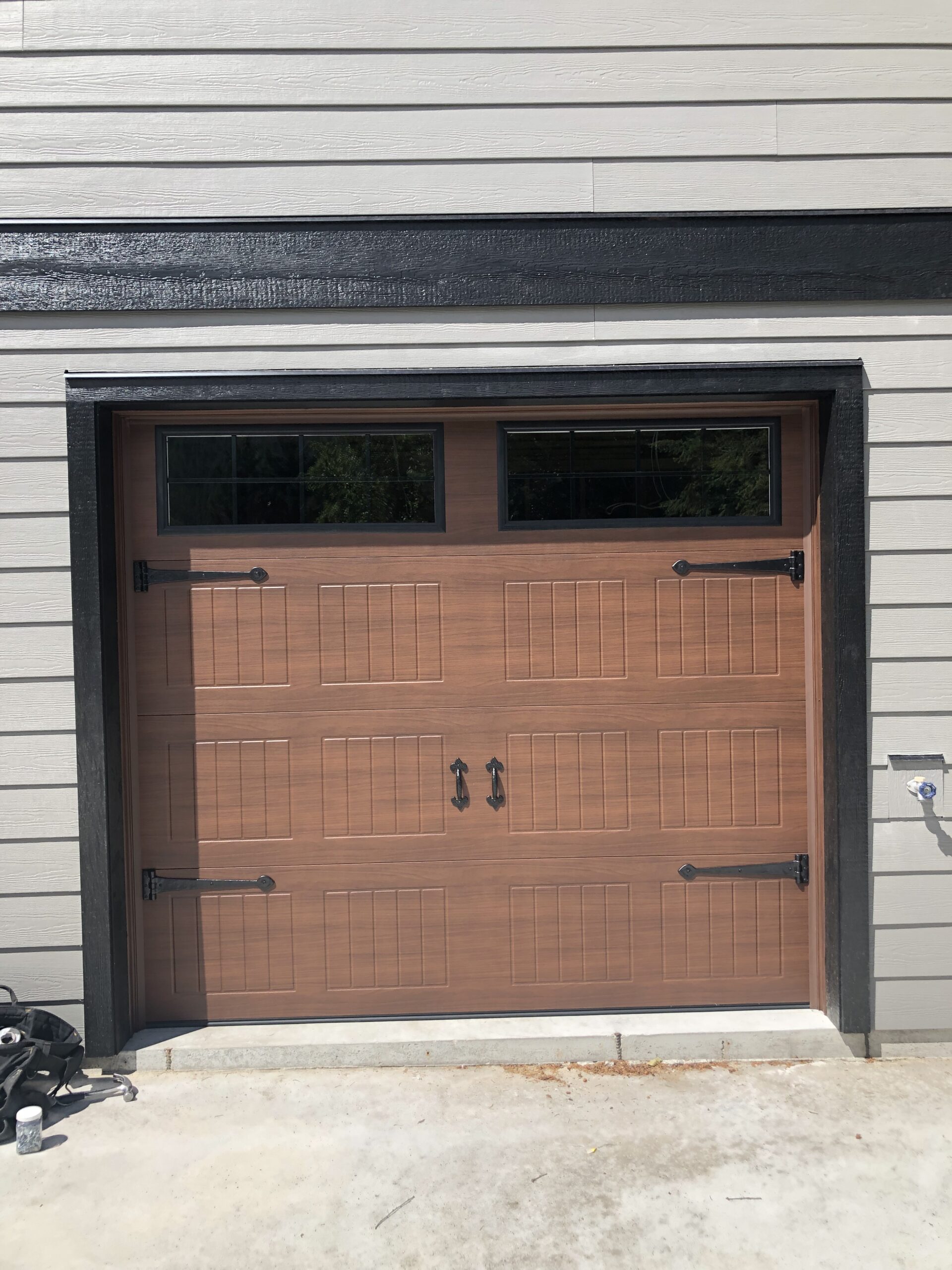 Faux wood carriage garage door with black handles and hinges. 