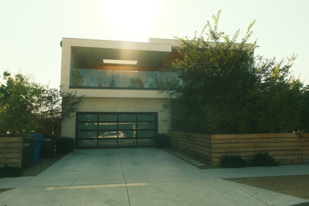 Modern house exterior with a glass garage door, surrounded by greenery, emphasizing residential garage door services in Armstrong, BC.